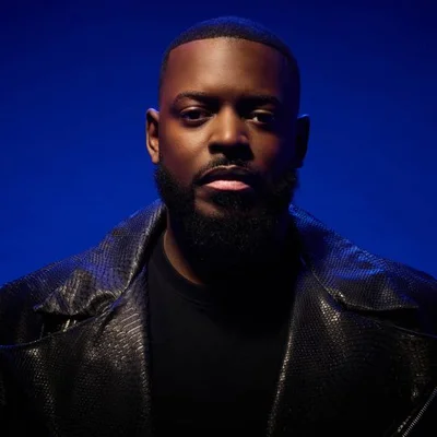 KeBlack en portrait sobre, veste noire texturée.