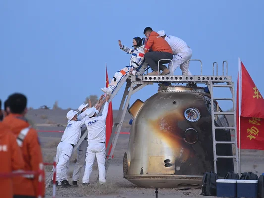Une astronaute de Shenzhou-21 sort de la capsule, assistée par l'équipe de récupération.