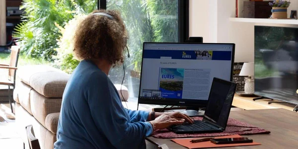 Un travailleur de plateforme numérique en télétravail, casque audio et ordinateur.