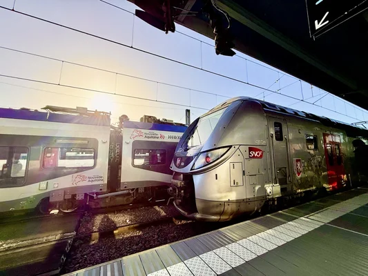 Trains SNCF et TER Nouvelle-Aquitaine en gare à l'heure du coucher du soleil, alors que les fortes chaleurs menacent les rails.