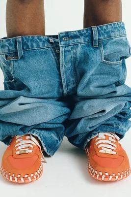 Sneakers orange Nike x Jacquemus associées à un jean baggy.