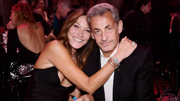 Carla Bruni et Nicolas Sarkozy enlacés lors d'un événement en soirée.