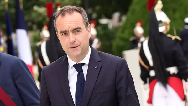 Sébastien Lecornu devant des gardes républicains et des drapeaux, lors d'une cérémonie officielle.