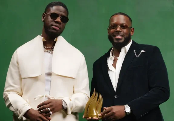 Franglish et KeBlack exhibent un trophée doré lors d'une séance promotionnelle.