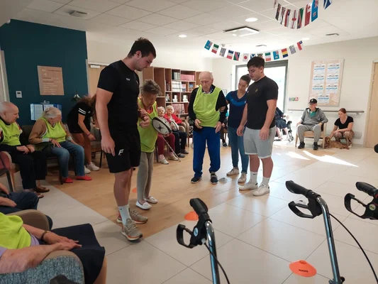 Des résidents d'Ehpad participent à une activité physique sur le thème du rugby, encadrés par des bénévoles.