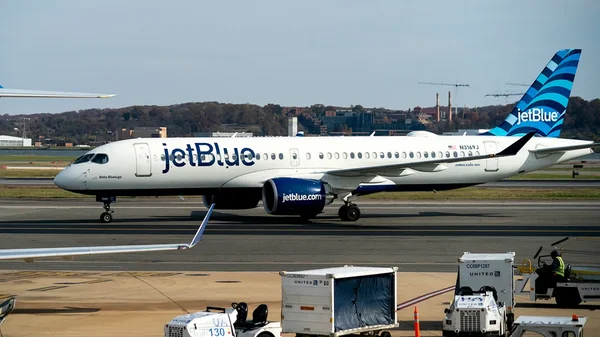 Un Airbus A220-300 de JetBlue en roulage sur une piste d'aéroport.
