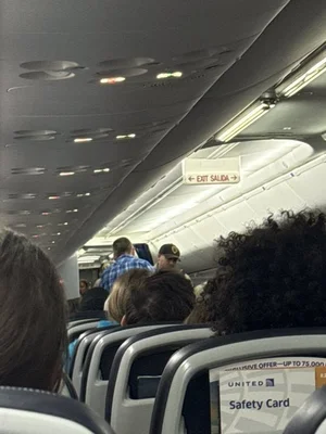Cabine d'un avion de United Airlines avec panneau de sortie de secours.