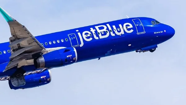 Un avion JetBlue Airways en vol, dérive arrière verte visible.