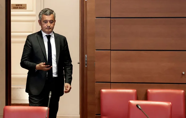 Gérald Darmanin consulte son téléphone en passant une porte.