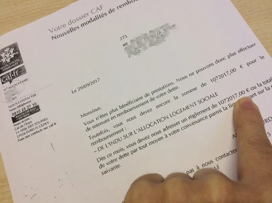 Courrier de la CAF précisant les modalités de remboursement, avec une main soulignant la ligne de dette.