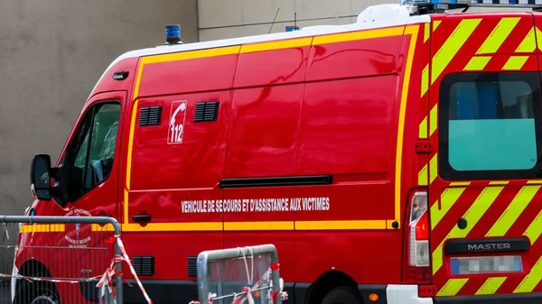 Véhicule de secours et d'assistance aux victimes (VSAV) garé derrière des barrières.