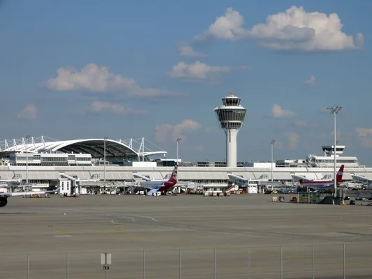 Vue d'ensemble de l'aéroport Franz-Josef-Strauß de Munich avec des avions au parking et la tour de contrôle.