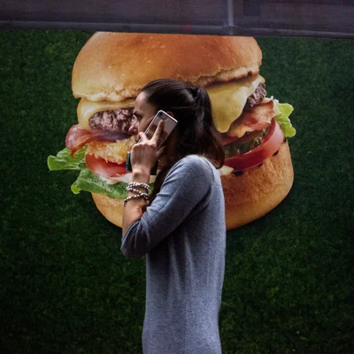 Une passante devant une publicité pour un cheeseburger à Amsterdam, illustrant les publicités visées par l'interdiction.