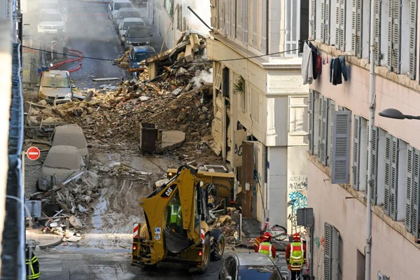 Engins de chantier et secouristes s'activent dans une rue marseillaise après l'effondrement d'un immeuble.