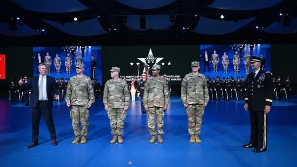 Cérémonie de remise de prix avec des militaires et un civil en costume sur scène.