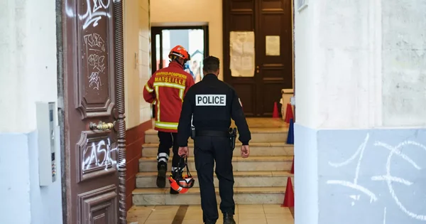 Un policier et un pompier marseillais montent les escaliers d'un immeuble endommagé par une explosion criminelle.