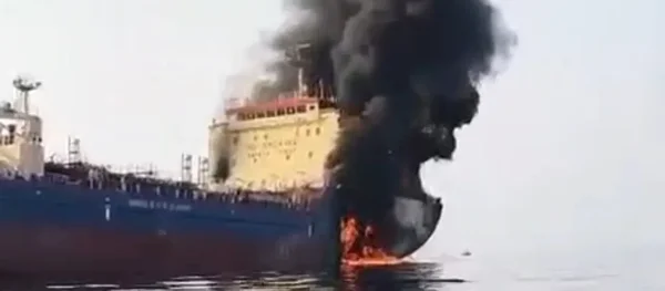 Pétrolier en feu dans le détroit d'Ormuz, projetant une épaisse fumée noire.