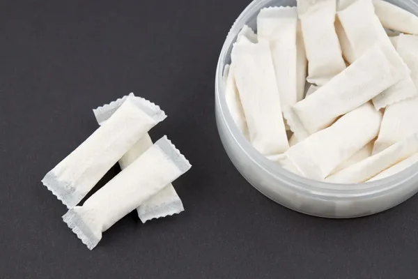 Sachets de nicotine blancs dans un contenant en plastique transparent.