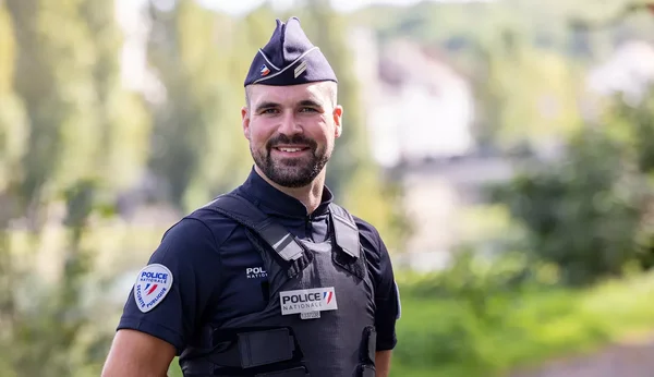 Un policier national en tenue d'uniforme, souriant à l'extérieur.