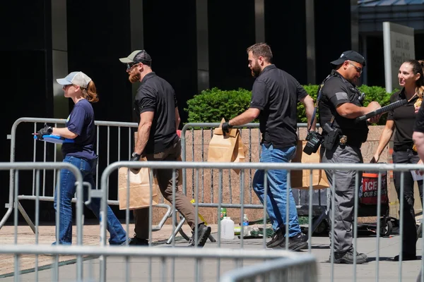 Des agents de sécurité et des civils derrière des barrières de contrôle lors d'une intervention près d'un bâtiment fédéral à New York.