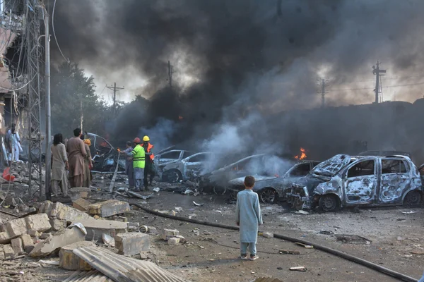 Conséquences de l'attaque à l'explosif d'un train au Pakistan : véhicules détruits et intervention des secours.