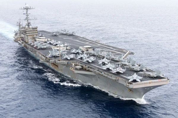 Un porte-avions américain de classe Nimitz en route vers le Moyen-Orient, avec des avions de chasse sur le pont.