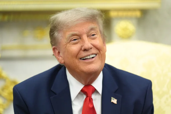 Donald Trump souriant, arborant une épingle du drapeau américain.