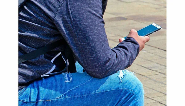 Utilisateur consultant un smartphone, illustrant l'accès mobile au réseau libertin Wyylde.