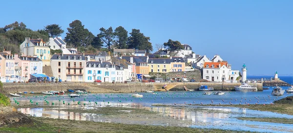 Le port de Belle-Île-en-Mer avec ses maisons colorées, son phare et ses bateaux à marée basse.