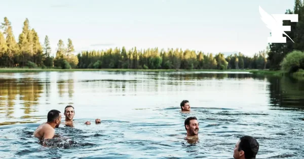 Groupe d'hommes nageant dans un lac entouré de forêt.