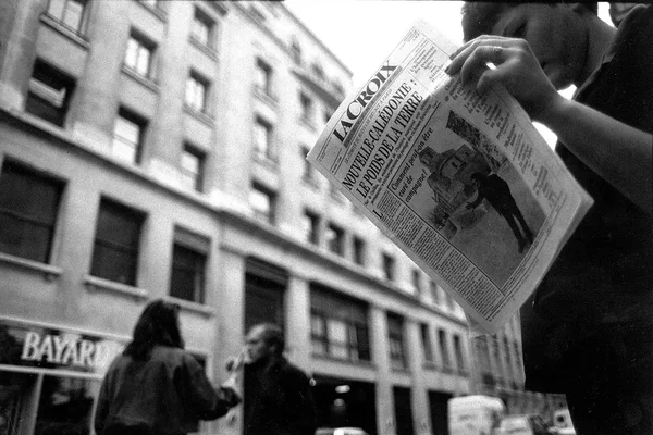 Un lecteur feuillette le journal « La Croix » devant l'immeuble Bayard.