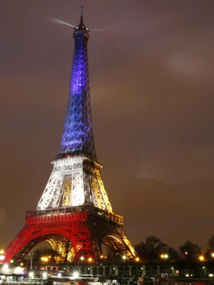La tour Eiffel parée des couleurs du drapeau français lors d'une illumination nocturne.