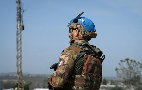Un soldat français Casque Bleu en observation devant une tour métallique.