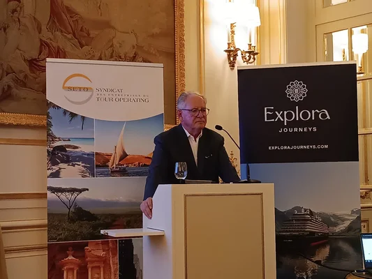 Un représentant du SETO s'adressant à la presse lors d'une conférence, entouré de bannières pour Explora Journeys.