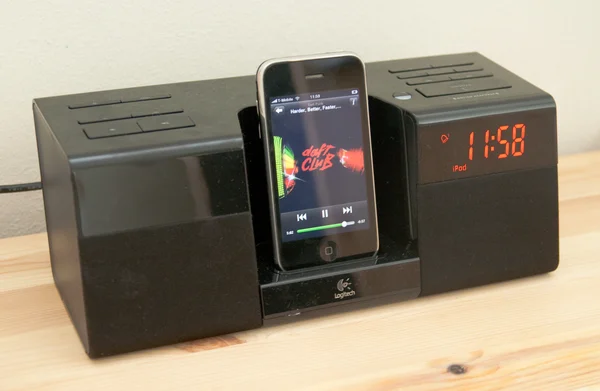 iPhone diffusant Spotify sur une station d'accueil Logitech Pure-Fi, posée sur une table en bois.