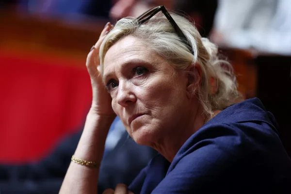 Marine Le Pen, les lunettes sur la tête, affiche un air sérieux.
