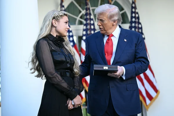 Donald Trump s'entretenant avec une femme devant des drapeaux américains