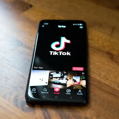 Smartphone affichant l'interface de l'application TikTok sur une table en bois.