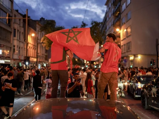 Supporters marocains fêtant la qualification sur une voiture dans une rue européenne.