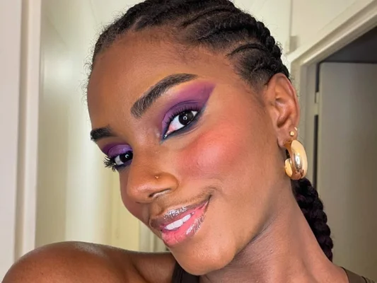 Portrait de Sandra Justine, Miss Guyane 2026, au maquillage violet et aux cheveux tressés.