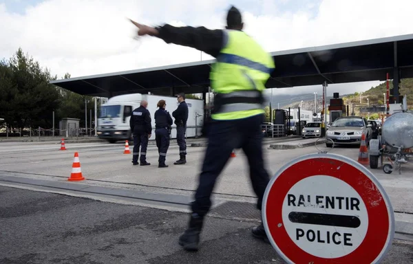 Contrôle aux frontières : des policiers dirigent la circulation à un péage.