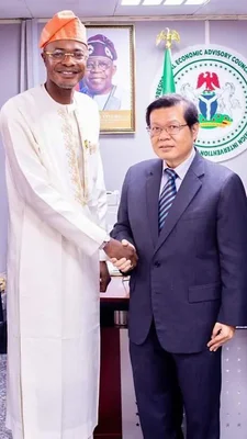 Poignée de main entre Adeniyi Adeyemi et un interlocuteur, devant l’emblème du Conseil économique présidentiel.