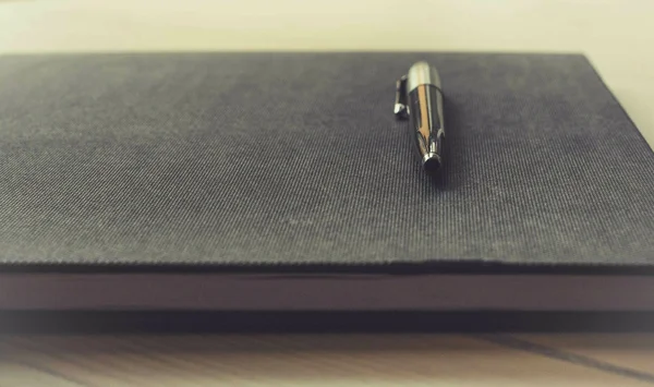 Un stylo argenté sur un carnet sombre, symbole de la pétition en ligne.