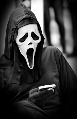 Ghostface, le tueur emblématique de la saga Scream, photographiant avec un appareil numérique.