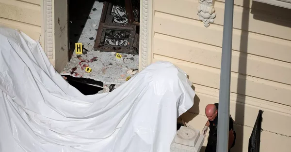 L'entrée de l'immeuble après l'explosion, avec des marqueurs de preuves et un drap blanc.