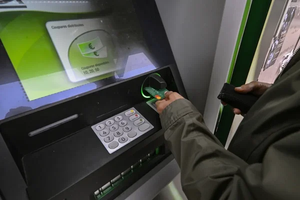 Insertion d'une carte bancaire verte dans un distributeur de billets.