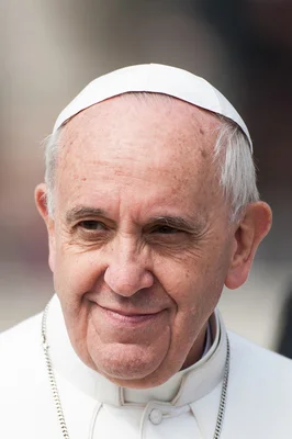 Portrait du pape François, souriant, en tenue pontificale blanche.