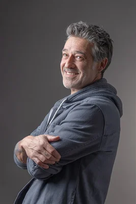 Stéphane Blancafort en studio, souriant, vêtu d'un sweat à capuche bleu.