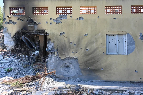 Le kibboutz Be'eri après l'attaque du 7 octobre 2023 : un bâtiment jaune criblé de balles et partiellement effondré.