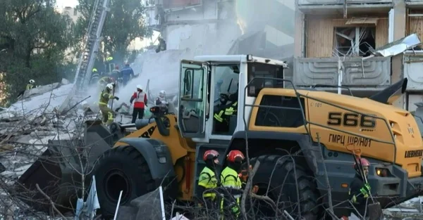 Une chargeuse-pelleteuse et des secouristes sur les lieux d'un immeuble effondré à Kiev après une attaque russe massive.